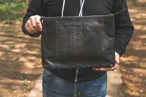Man with snakeskin python handbag on nature background. 写真素材