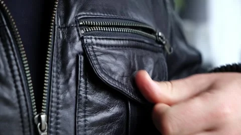 The man snaps the pocket of his leather jacket. Metal button in pocket close-up Stock Footage 323799422