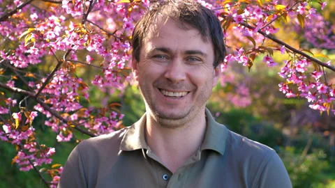 Man Sneezing in Front of Blossoming Cherry Trees in Springtime, Stock Footage 280584921