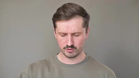 A man sniffs a container of sushi rolls and winces at the unpleasant odor. A 動画素材 337556354