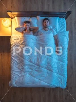 The man snore near the wife on the bed. evening night time. view from above Stock Photos