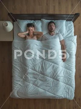The man snore near the woman on the bed. view from above Stock Photos
