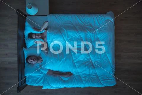 The man snore near the woman on the bed. night time. view from above Stock Photos