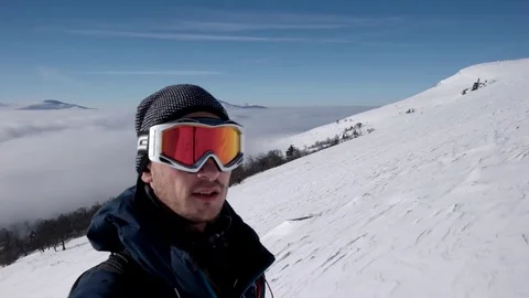 Man in Snow Mask is Making Selfie While Winter Hike Above the Clouds With a Stock Footage 71620334