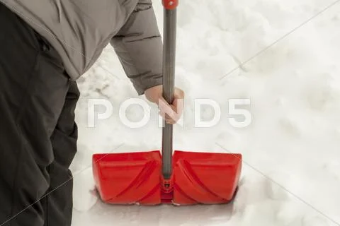 Man with a snow shovel near the snow pile Stock Photos