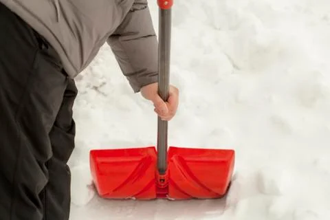 Man with a snow shovel near the snow pile Stock Photos