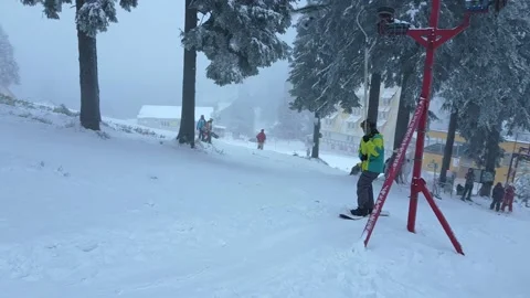 Man on snowboard going up by hill pulling with yoke Stock Footage 148996731