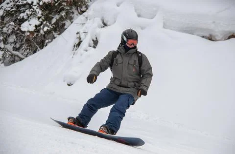 A man on a snowboard rides down the side of the mountain Stock Photos
