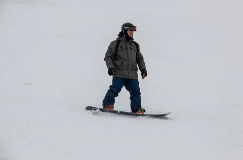 A man on a snowboard rides down the side of the mountain Stock Photos