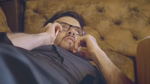 Man on the sofa answering the phone Stock Footage 73747283
