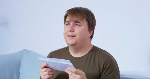 Man sofa bill envelope notice of debt dismissal upset sighs shakes head bad news Stock Footage 232443347