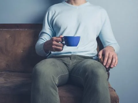 Man on sofa drinking coffee Photos