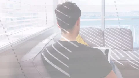Man on sofa facing balcony, sunlight shifting through blinds causing tech work Stock Footage 333211482