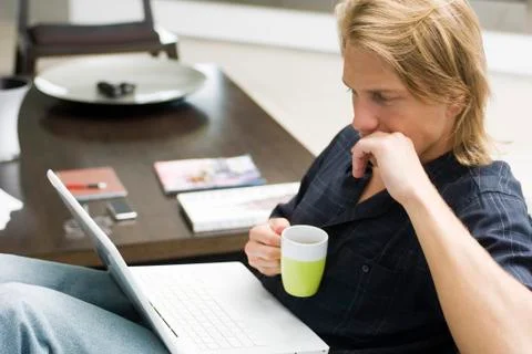 Man on sofa with laptop computer and cup of coffee Foto stock