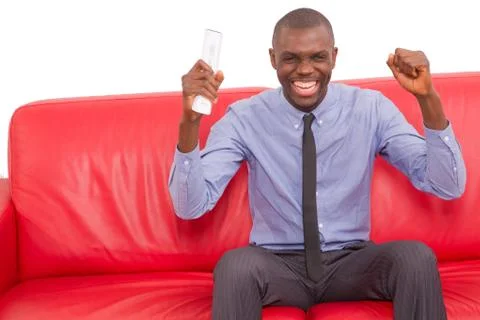 Man on the sofa with remote control rejoice Stock Photos