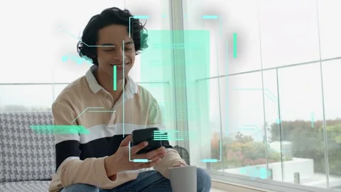 Man on sofa tapping phone, checking messages, causing cyan AR HUD aligning over Stock Footage 333998940