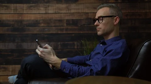 Man in a soft chair using phone Stock Footage 85470998
