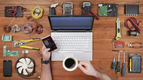 Man software engineer working at a desk with a phone, a laptop and a cup of Stock Footage 72415584