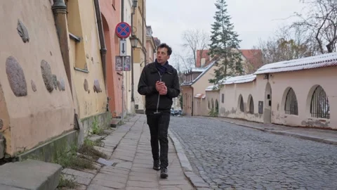 Man on a solo walk exploring a quiet historic street in Warsaw Stock Footage 311193071