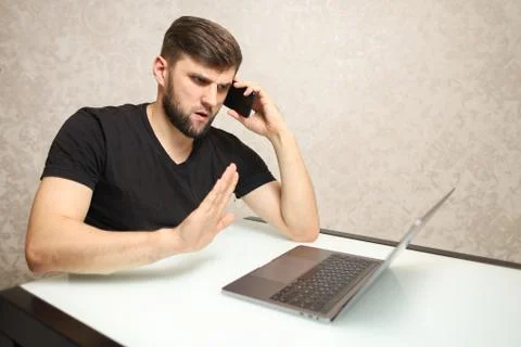 A man solves important business on the phone while sitting at a laptop Stock Photos