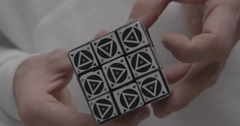 Man solves Rubik cube with triangles on light background Stock Footage 150754440