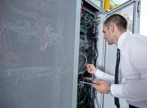 Man solving a problem with wires in a modern datacenter server room Illustrazione stock