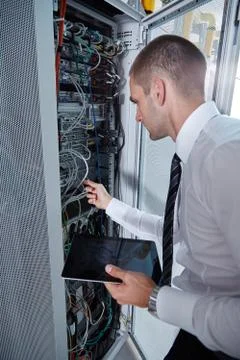 Man solving a problem with wires in a modern datacenter server room Stock Photos