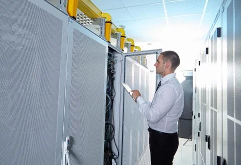 Man solving a problem with wires in a modern datacenter server room Stock Photos