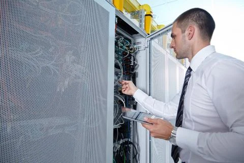 Man solving a problem with wires in a modern datacenter server room Stock Photos