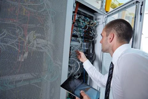 Man solving a problem with wires in a modern datacenter server room Stock Photos