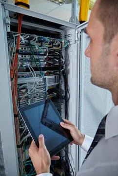 Man solving a problem with wires in a modern datacenter server room Stock Photos