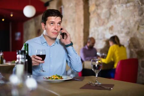 Man solving problems on phone while dining in restaurant 写真素材