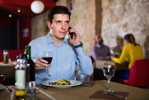 Man solving problems on phone while dining in restaurant Stockfoto's