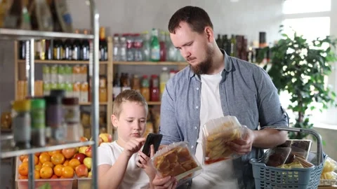 Man with son customer at shop scans QR code on poultry meat joints using phone Video stock 329397709