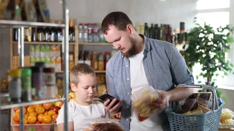 Man with son customer at shop scans QR code on poultry meat joints using phone Vídeo Stock 344776476