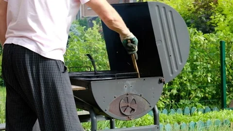 A man is sorting coals on a grill in the summer on the street. Stock Footage 130669761