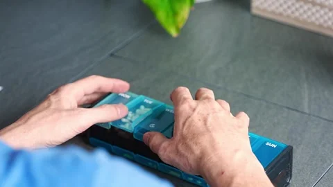 Man sorting his pills and supplements into a weekly pill organizer. Concept of Stock Footage 312913771