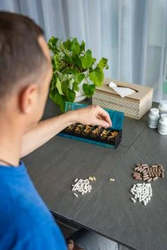 Man sorting his pills and supplements into a weekly pill organizer. Concept of Stock Photos
