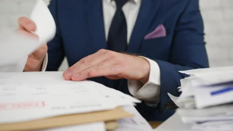 A man sorting paperwork in an office. The unrecognizable businessman is 스톡 동영상 220940161