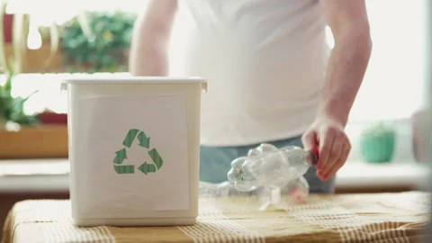 Man sorting plastic bottles and paper waste into recycling bins at home kitchen, Stock Footage 332677347