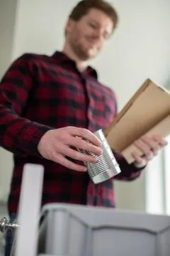 Man Sorting Recycling Into Kitchen Bin At Home Foto stock
