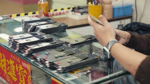 Man sorting stacked smartphone components at repair shop counter Stock Footage 328963520