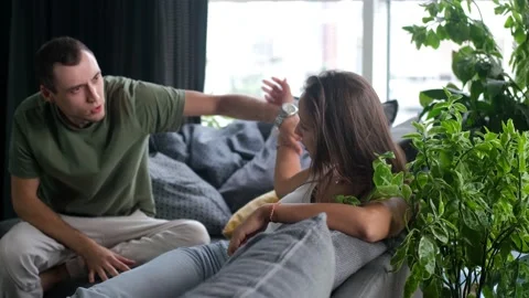 A man sorts things out with his woman, sitting on the sofa in the living room. A Stock Footage 201828690