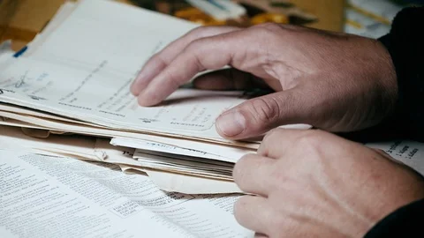 Man sorts through stack of papers and files, opens envelope with letter Stock Footage