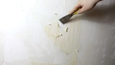A man with a spatula tears off the wallpaper from the wall Stock Footage 158431142