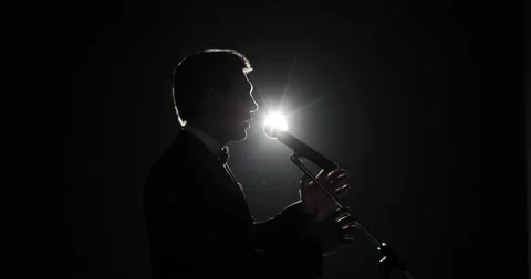 Man speaker in suit speaking microphone standing on stage in dark in spotlight. 스톡 동영상 138322233
