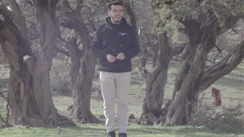 Man Speaking Among Ancient Twisted Argan Trees in Morocco Vidéo 332775234