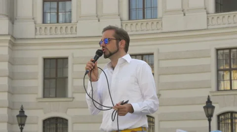 Man speaking into a microphone in Michaelerplatz, Vienna Stock Footage 59181407