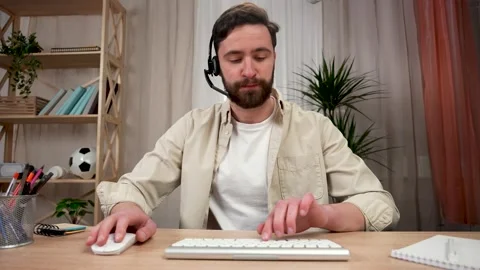A man speaking on a webcam in wireless headphones with a microphone, waves his Stock Footage 150972985