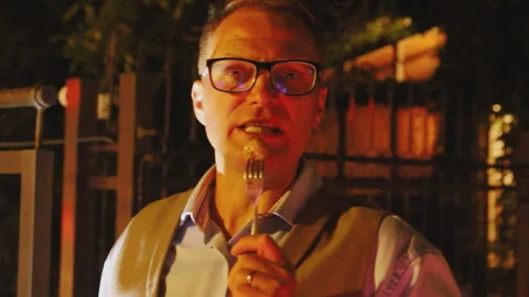 The man speaks into a fork with a vegetable impaled on the fork Stock Footage 136819114